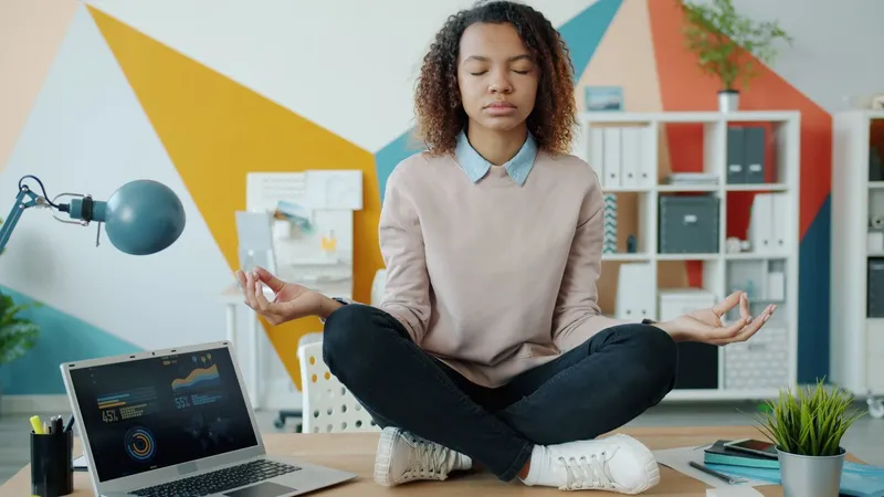 An employee meditating at her desk in a modern office