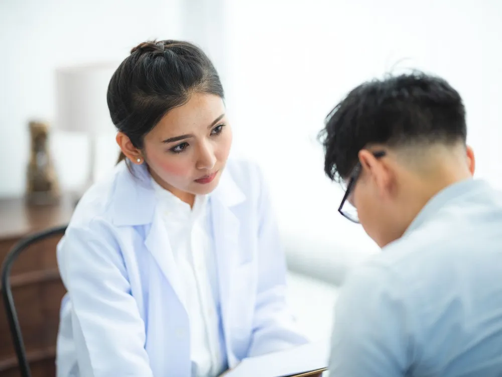 Doctor in a white coat listening to a patient during a consultation