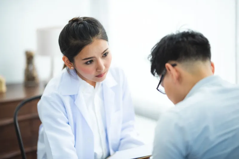 Doctor in a white coat listening to a patient during a consultation