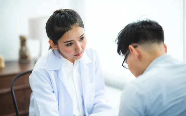 Doctor in a white coat listening to a patient during a consultation