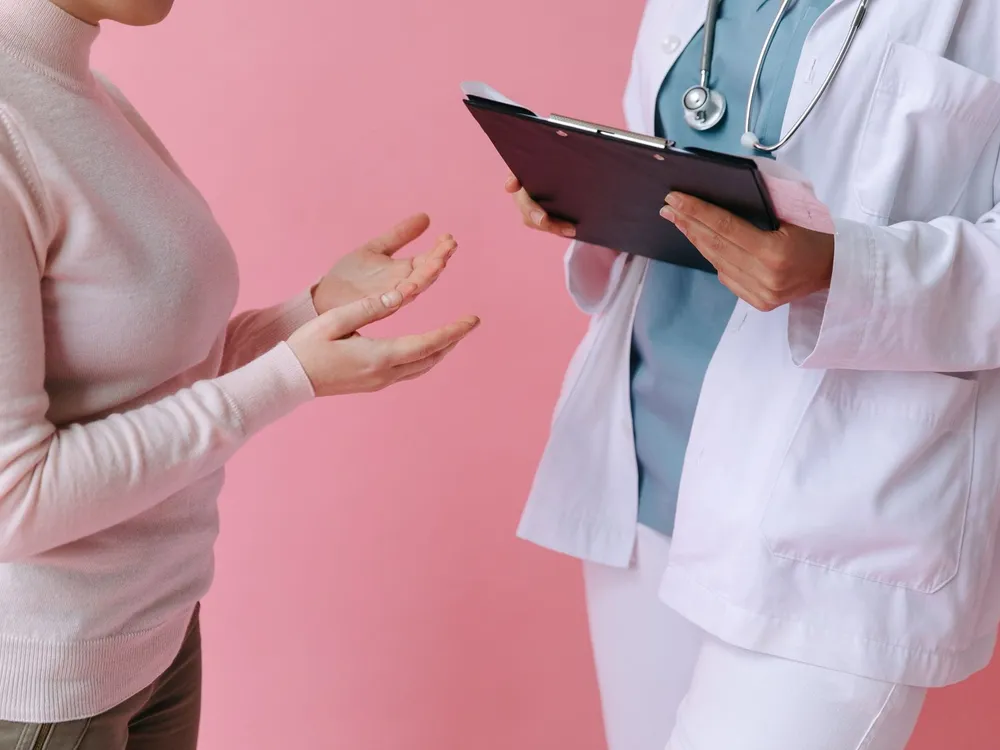 Doctor holding a clipboard while a patient describes symptoms