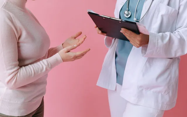 Doctor holding a clipboard while a patient describes symptoms