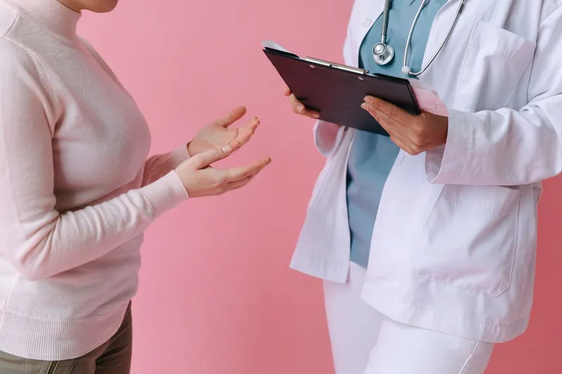 Doctor holding a clipboard while a patient describes symptoms